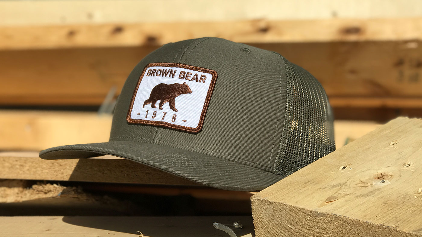 Earth tone hat with embroidered bear crossing patch