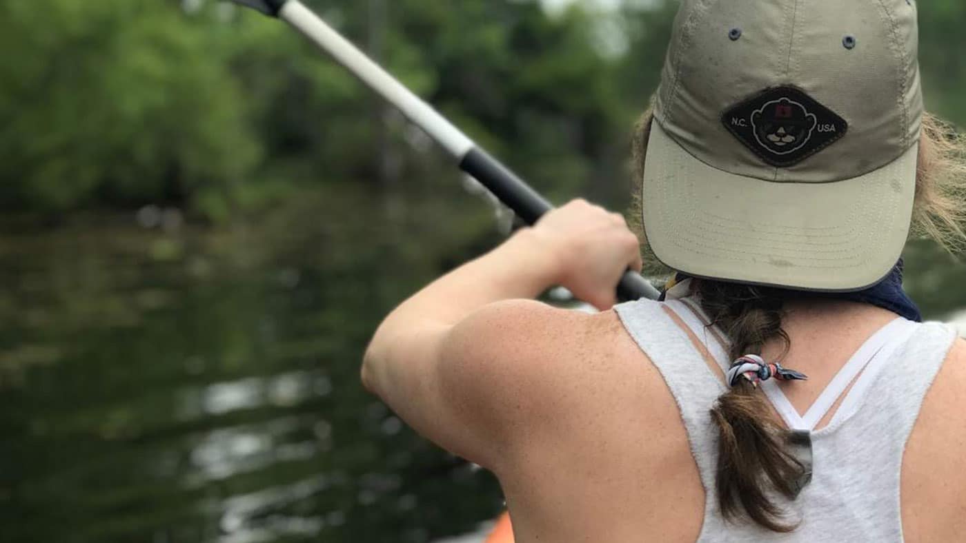 Woman wearing waterproof cap kayaking in the mountains