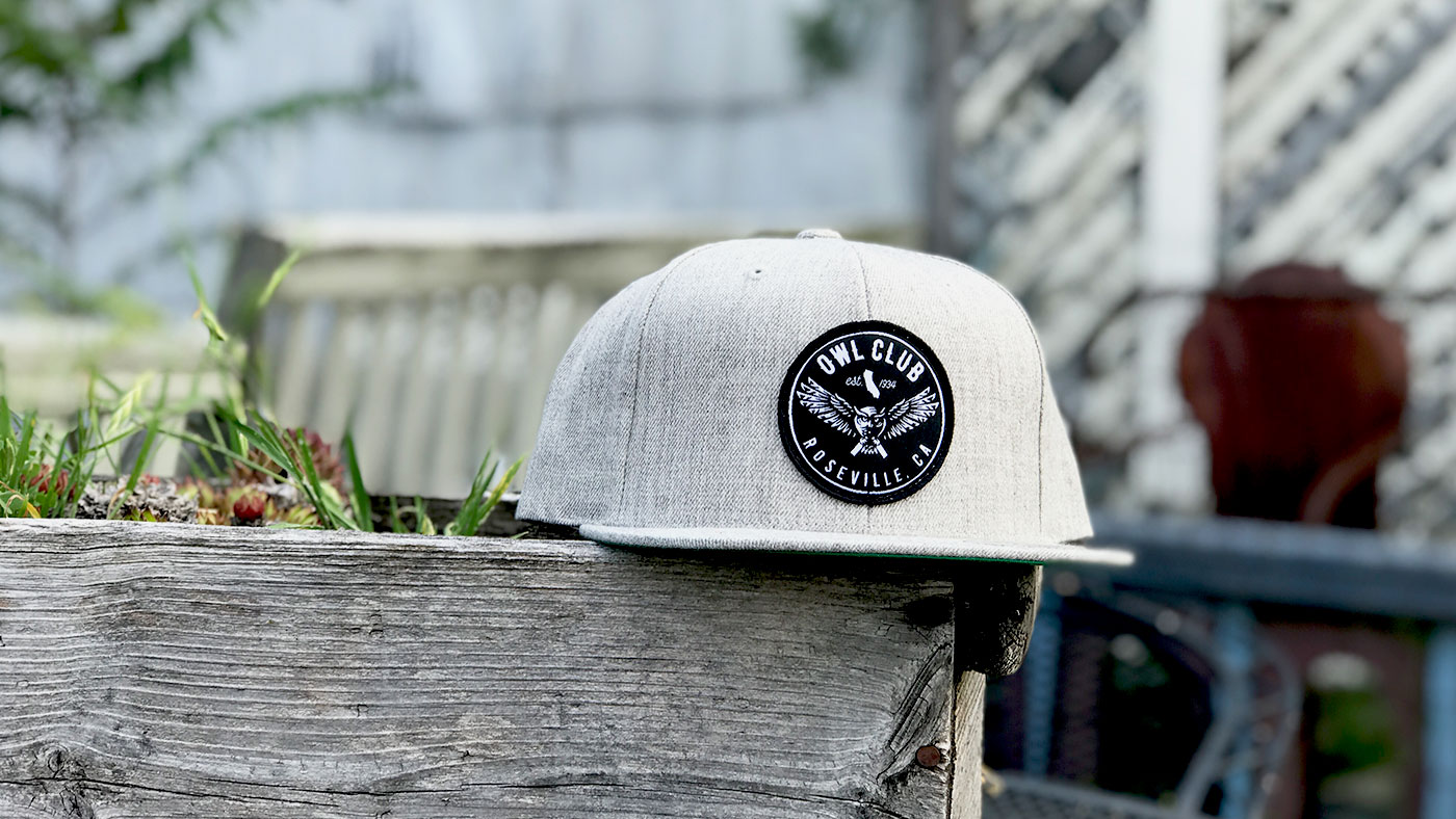 Custom Flat Bill Snapback Hat Grey hat with black patch in a garden