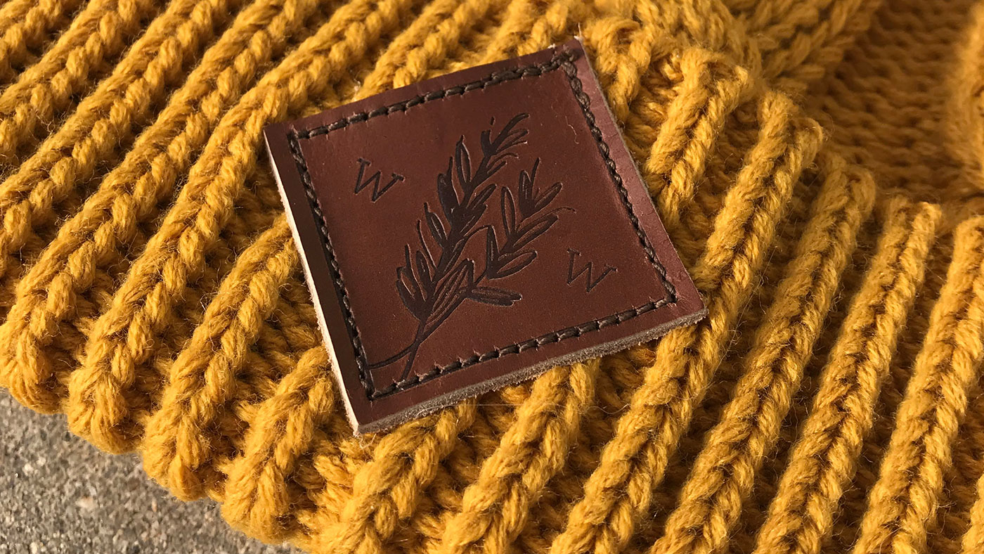 Custom Leather Patch Beanies Closeup of a leather patch with detailed logo on gold beanie