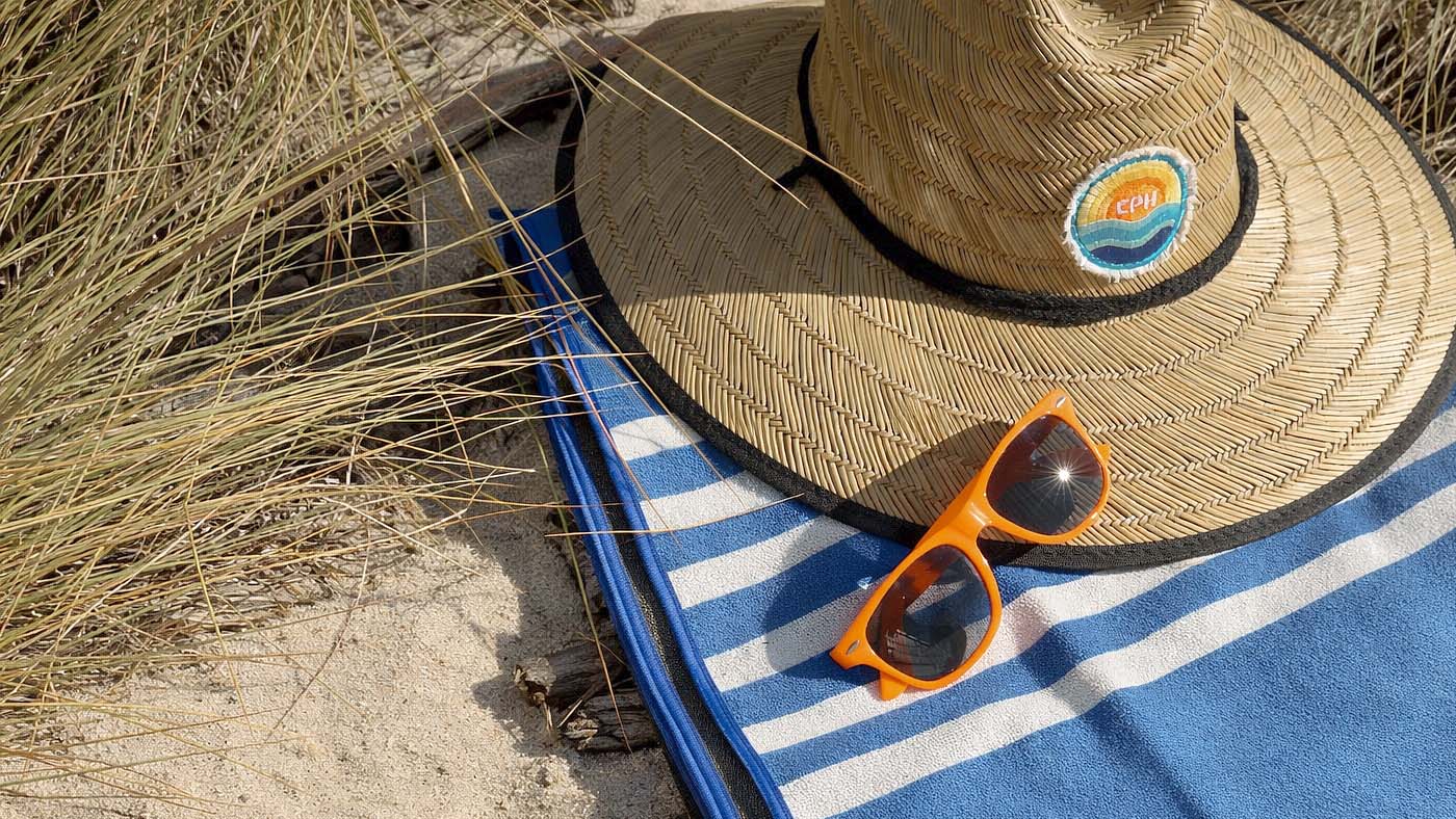 Straw hat on sandy beach with custom company logo