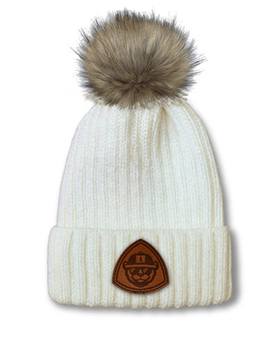 Port Authority faux-fur pom beanie with leather patch branding.