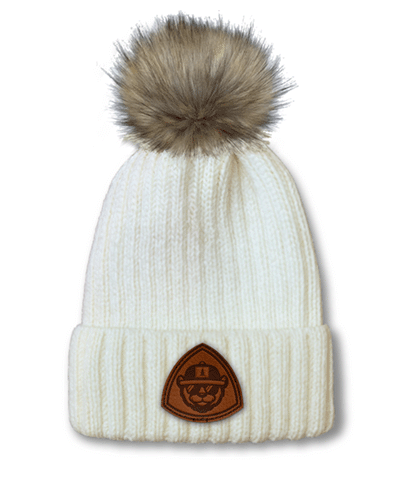 Port Authority faux-fur pom beanie with leather patch branding.